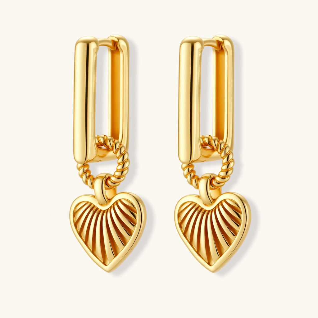 Gold-plated huggie earrings with textured heart charms featuring radiating sunburst patterns on white background.